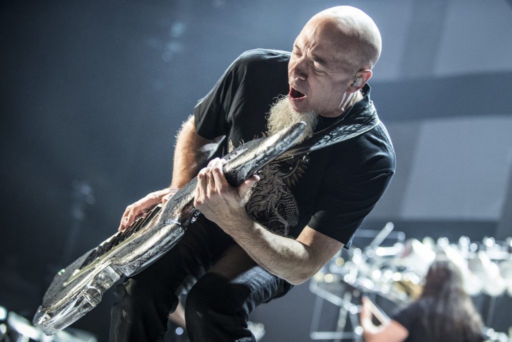 Man with goatee in black shirt playing keytar at an angle on stage.