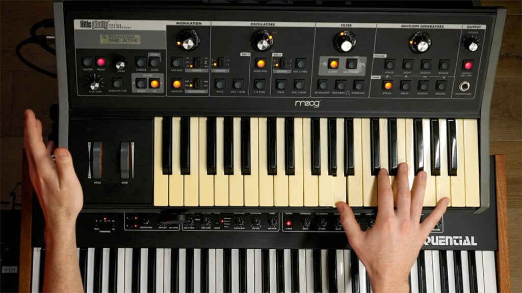 Overhead view of a small synthesizer keyboard with knobs, buttons, switches, and wheels.